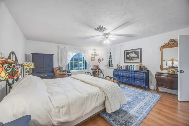 a spacious bedroom with a bed a table and a chandelier