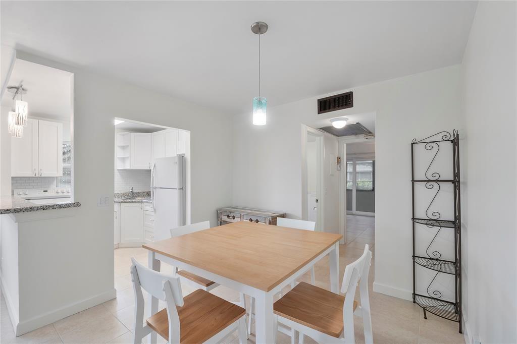 373 Tilford R, Unit 373 Deerfield Beach, FL 33442 - Photo 7 of 36 a kitchen with stainless steel appliances a dining table chairs and white cabinets