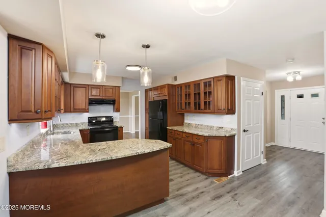 a kitchen with stainless steel appliances granite countertop a stove top oven a sink dishwasher and a microwave oven with large wooden cabinets