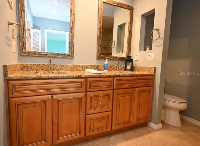 a bathroom with a granite countertop toilet sink and mirror