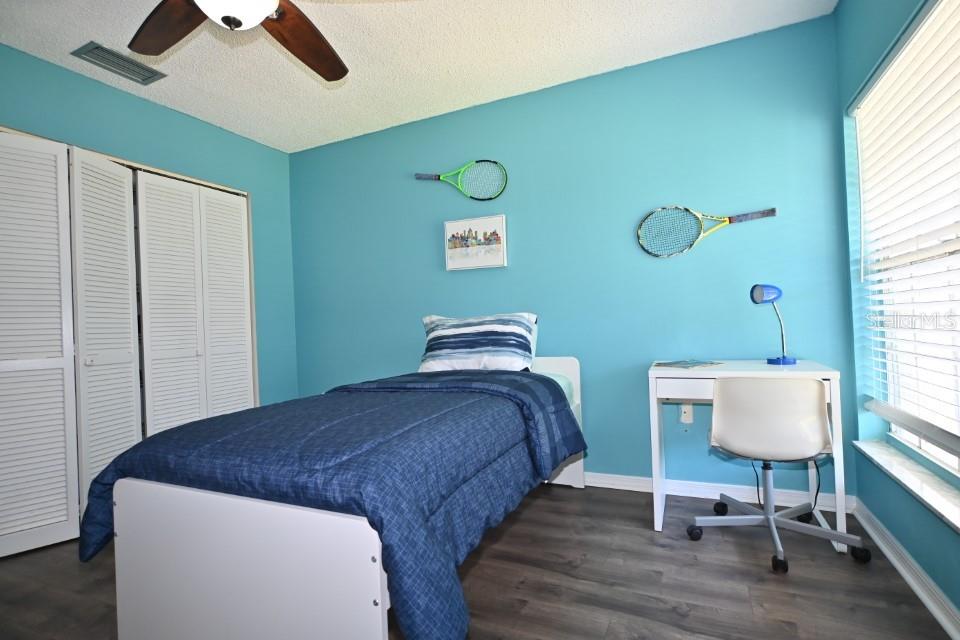 5348 Saddlebrook Way, Unit 2 Wesley Chapel, FL 33543 - Photo 27 of 38 a bedroom with a bed and a lamp on table