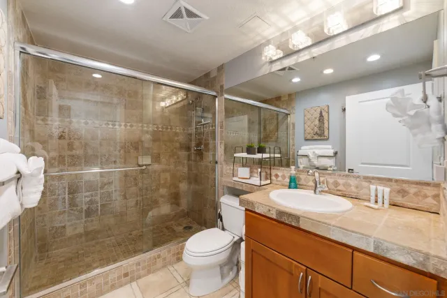 a bathroom with a shower sink vanity mirror and toilet