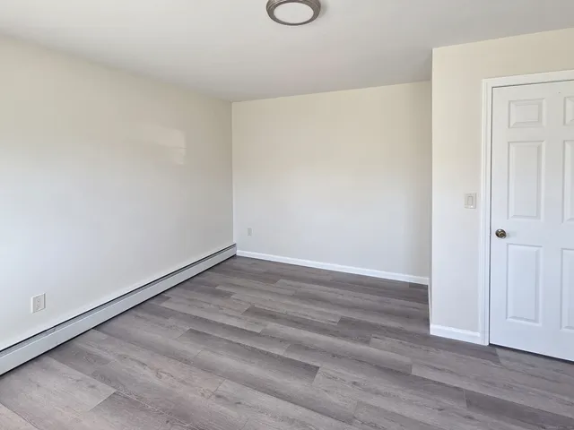 a view of an empty room with wooden floor and closet