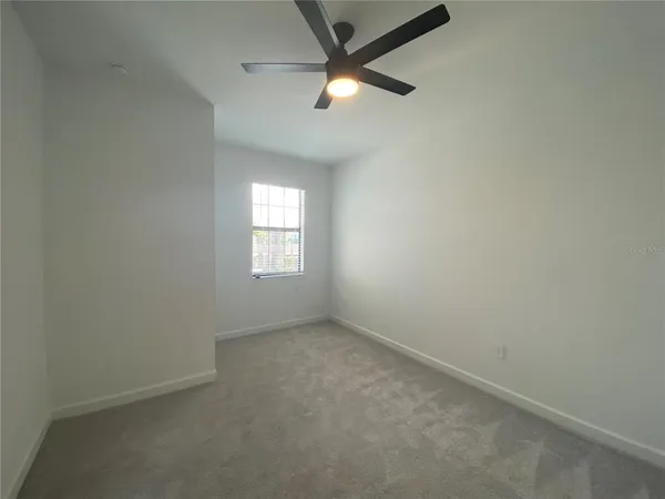 an empty room with a window and a fan