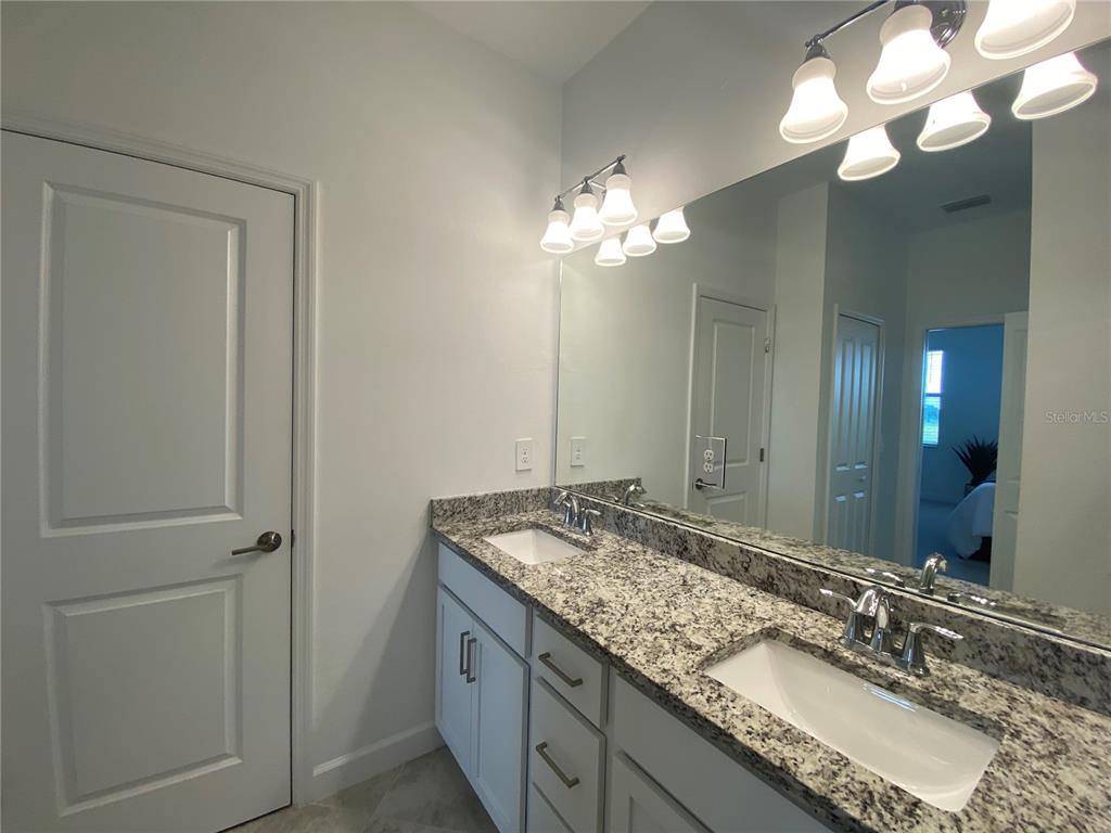 15216 Lyla Terrace Lakewood Ranch, FL 34211 - Photo 12 of 15 a bathroom with a granite countertop double vanity sink and a mirror