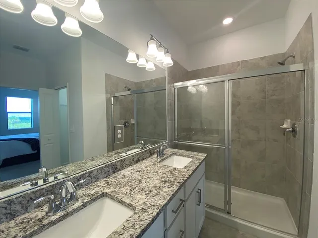 a bathroom with a granite countertop sink a mirror and a shower