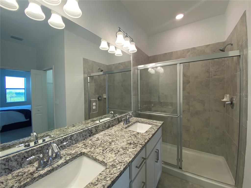 15216 Lyla Terrace Lakewood Ranch, FL 34211 - Photo 15 of 15 a bathroom with a granite countertop sink a mirror and a shower