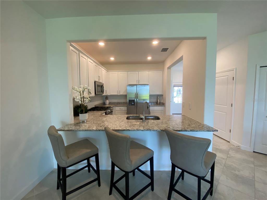15216 Lyla Terrace Lakewood Ranch, FL 34211 - Photo 4 of 15 a dining hall with stainless steel appliances granite countertop a dining table and chairs