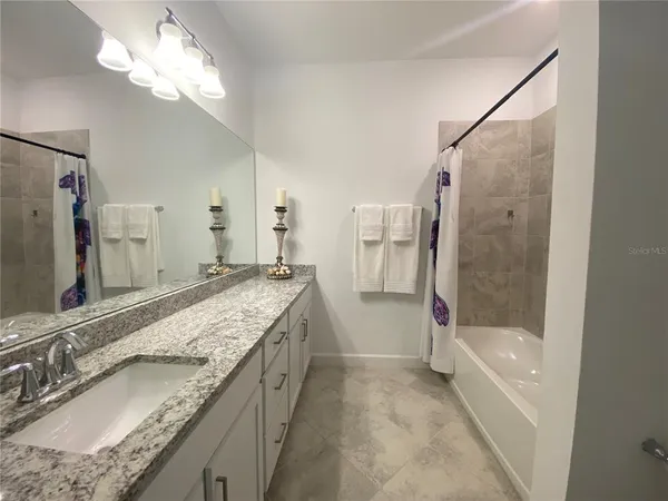 a bathroom with a granite countertop bathtub shower sink and mirror