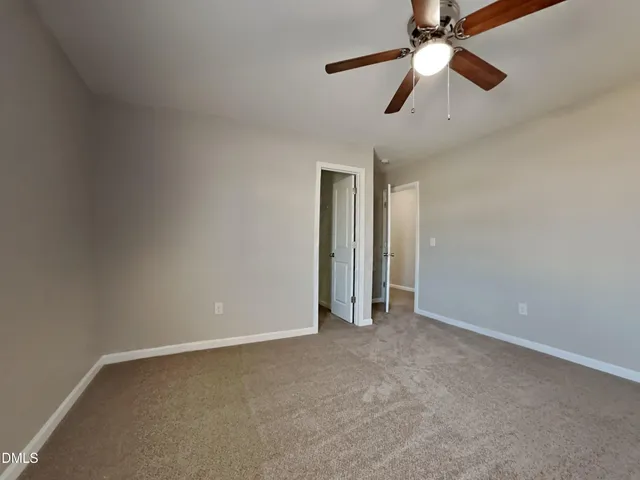 an empty room with closet and a chandelier fan