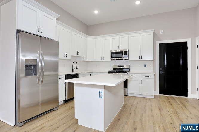 385 Passaic Avenue, Unit 6 Lodi, NJ 07644 - Photo 10 of 23 a kitchen with cabinets stainless steel appliances and wooden floor