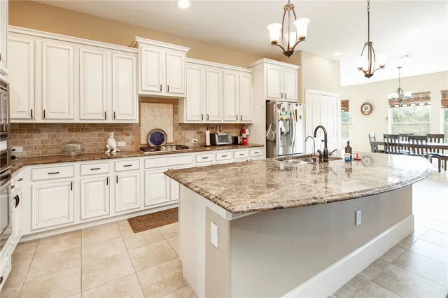 a kitchen with kitchen island granite countertop a sink a counter top space cabinets and stainless steel appliances