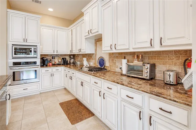 a kitchen with granite countertop a sink stainless steel appliances and cabinets