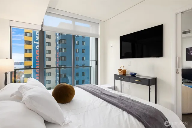 a bedroom with a bed a television and a large window