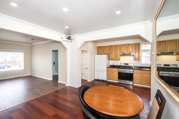 a view of a kitchen with kitchen island a sink wooden floor and stainless steel appliances