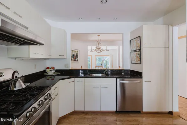 a kitchen with granite countertop a sink a stove and cabinets