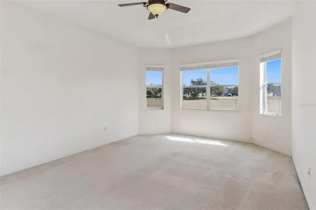 an empty room with a ceiling fan and carpet