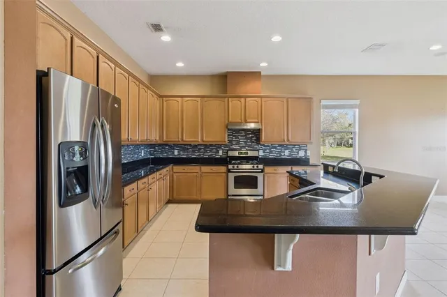 a kitchen with stainless steel appliances granite countertop a refrigerator a sink and a stove