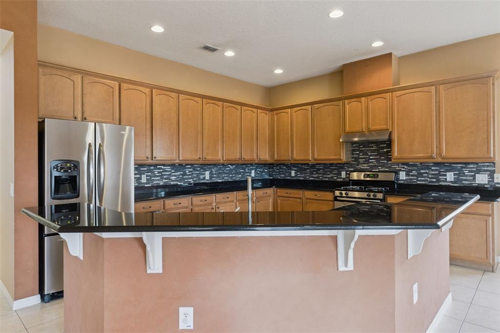 3643 Peaceful Valley Drive Clermont, FL 34711 - Photo 16 of 52 a kitchen with stainless steel appliances granite countertop a refrigerator a sink and a stove