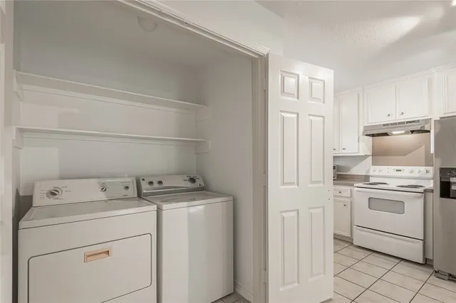 an empty room with chandelier fan and windows