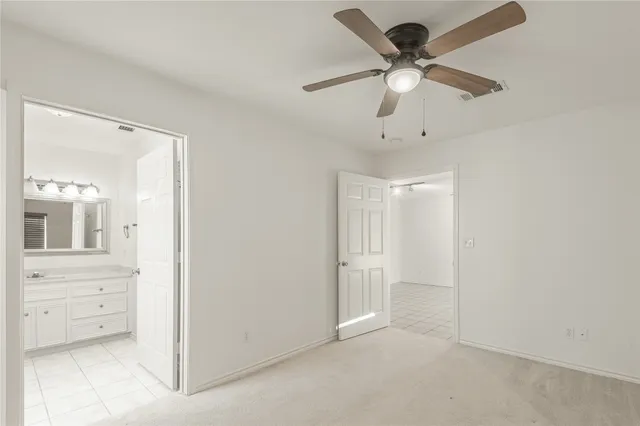 an empty room with wooden floor chandelier fan and windows