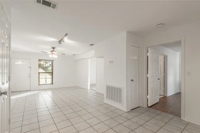 an empty room with windows and fan