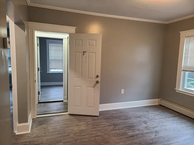 an empty room with wooden floor cabinet and windows