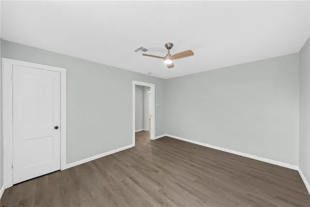 an empty room with wooden floor and ceiling fan