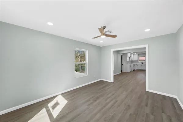 a view of an empty room with a window and wooden floor