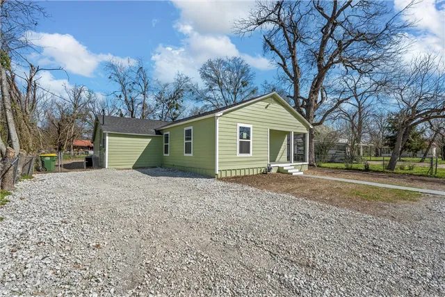 a view of a yard in front of a house with a large tree
