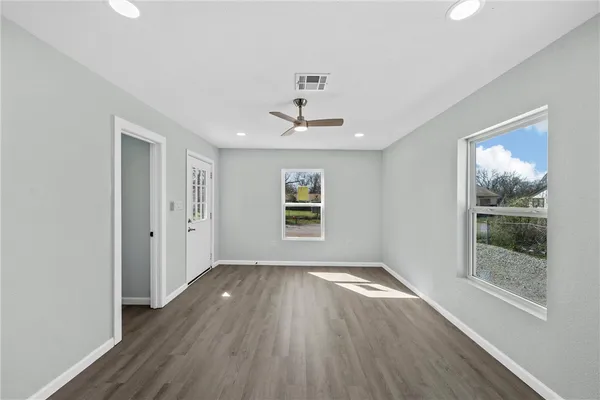 an empty room with wooden floor and windows