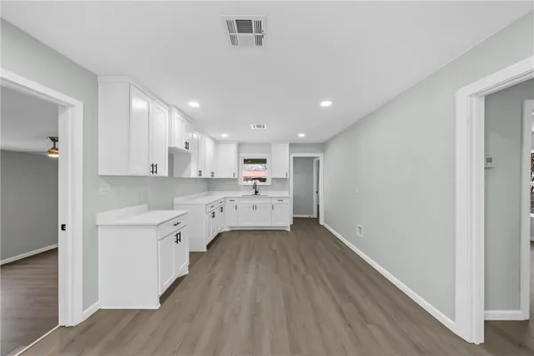 a large white kitchen with a sink dishwasher a stove refrigerator and cabinets