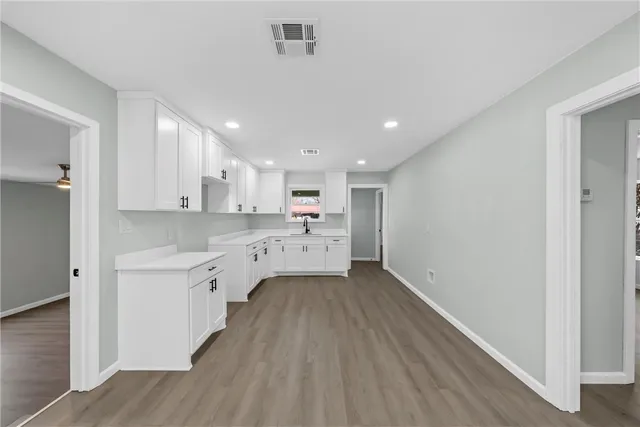 a large white kitchen with a sink dishwasher a stove refrigerator and cabinets