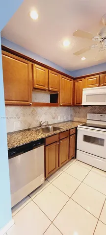 a kitchen with granite countertop a stove a sink and a microwave