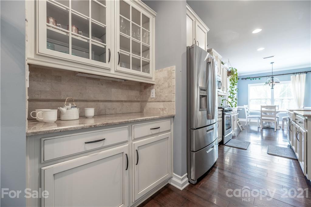 8049 Bryson Road, Unit 117 Indian Land, SC 29707 - Photo 15 of 40 a kitchen with stainless steel appliances granite countertop a refrigerator a sink dishwasher a stove and a dining table with wooden floor