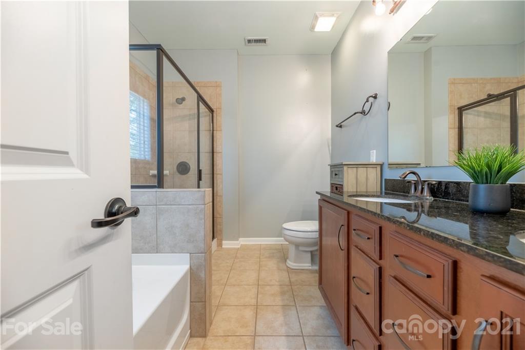 8049 Bryson Road, Unit 117 Indian Land, SC 29707 - Photo 30 of 40 a spacious bathroom with a granite countertop sink a toilet a mirror and shower