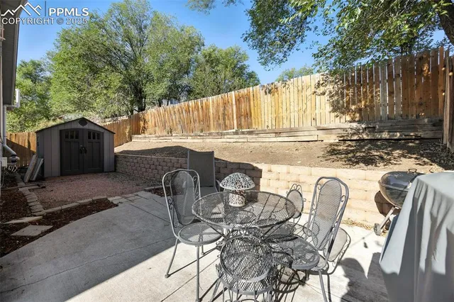 a view of a patio with table and chairs and wooden fence