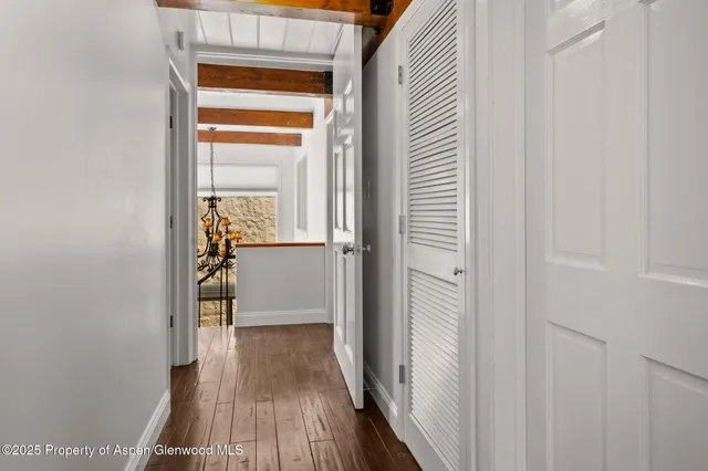a view of a hallway with wooden floor and a bathroom