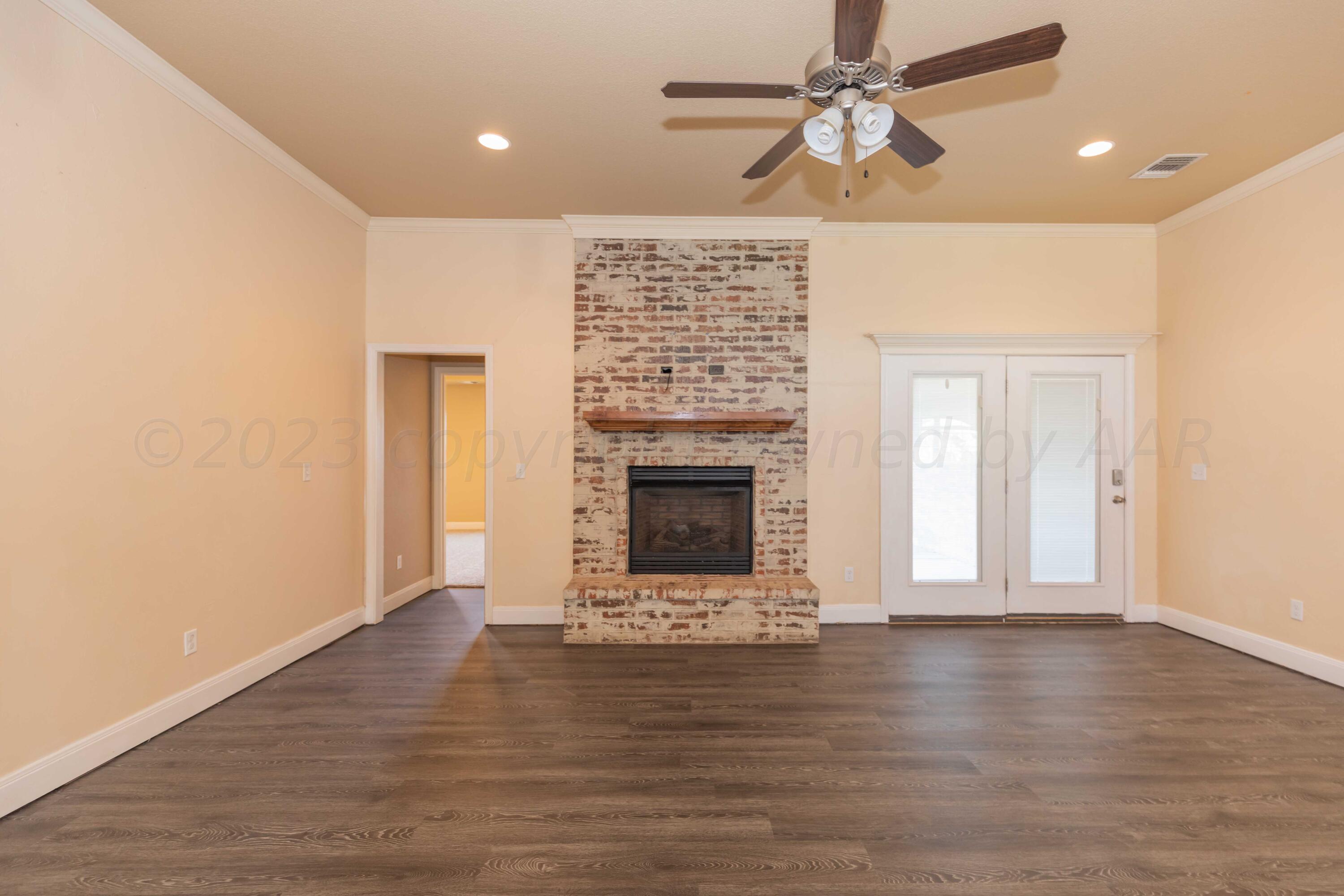 3904 Arden Road Amarillo, TX 79118 - Photo 7 of 45 a view of a livingroom with wooden floor a ceiling fan and a fireplace
