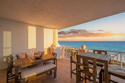 a view of a balcony with a dining table and chairs with wooden floor