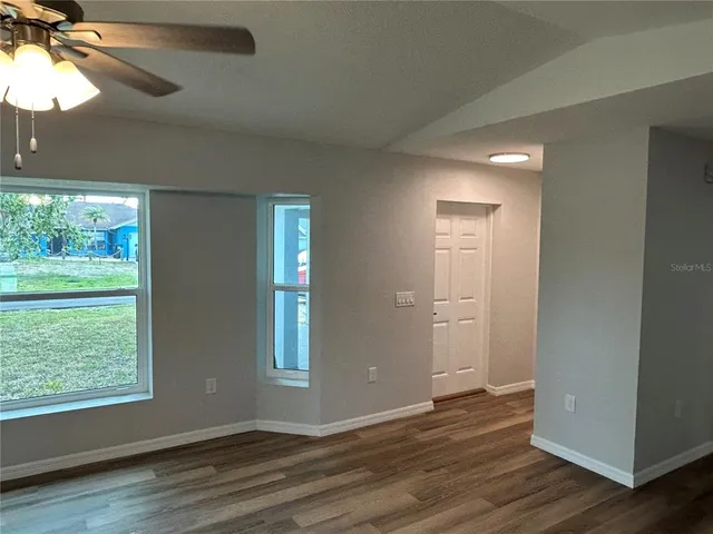 a view of an empty room with wooden floor and a window