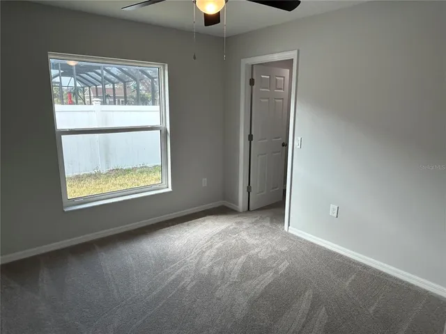 an empty room with a window and a fan
