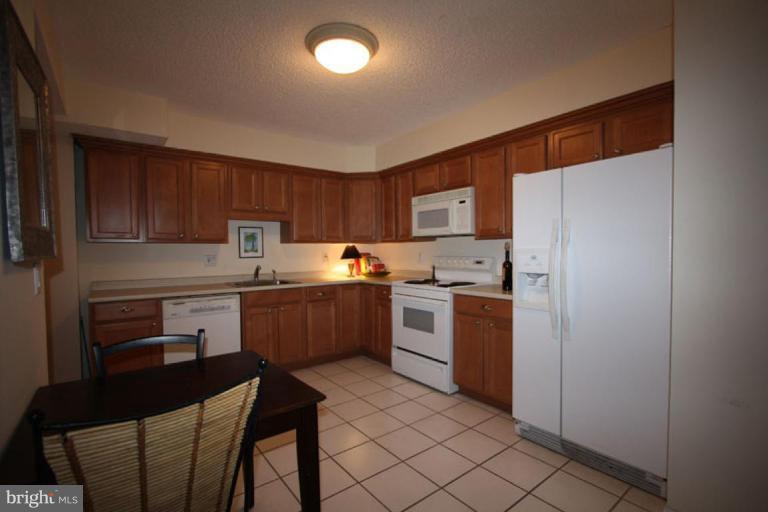 1045 31st Street Northwest, Unit 202 Washington, DC 20007 - Photo 2 of 21 a kitchen with a refrigerator a stove top oven a sink dishwasher and wooden cabinets