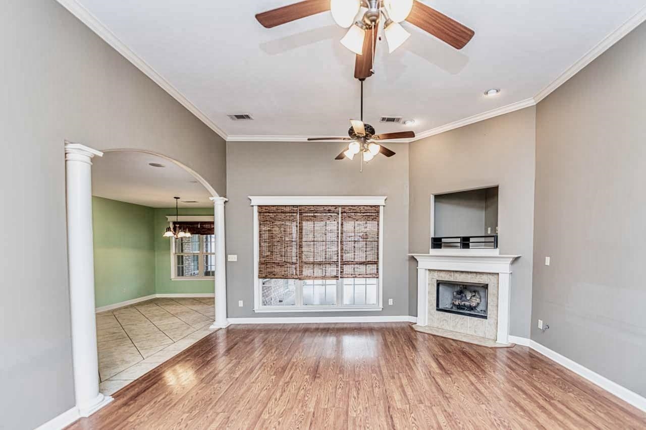 3876 West Union Road Millington, TN 38053 - Photo 24 of 40 Unfurnished living room featuring crown molding, arched walkways, light wood-style flooring, and a high end fireplace