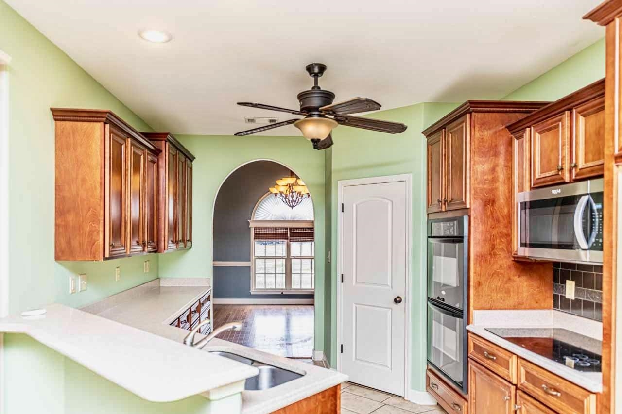 3876 West Union Road Millington, TN 38053 - Photo 29 of 40 Kitchen featuring black appliances, arched walkways, a ceiling fan, a peninsula, and light tile patterned floors