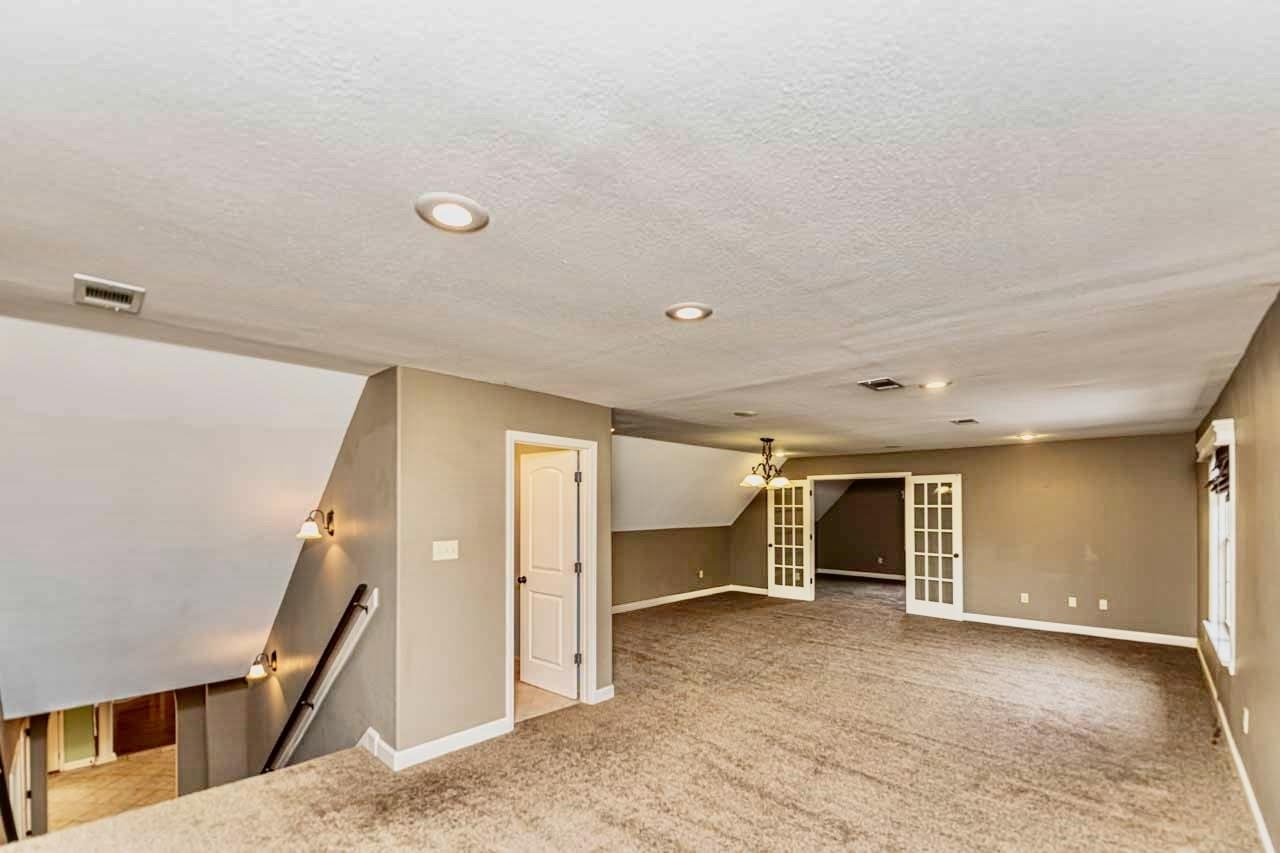 Unfurnished room featuring french doors, a textured ceiling, light carpet, a chandelier, and recessed lighting