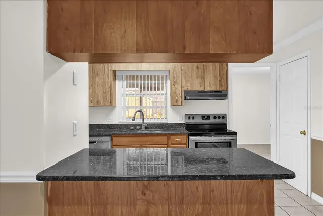 a kitchen with stainless steel appliances granite countertop a stove a sink and a microwave
