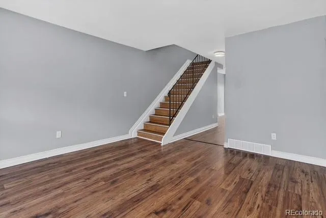 a view of an empty room with wooden floor and stairs