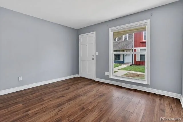 a view of an empty room with wooden floor and a window