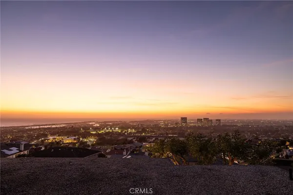 a view of a backyard with couches table and chairs under an umbrella with a fire pit